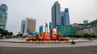 Sejumlah pengendara sepeda motor melintasi dekorasi Tahun Baru Imlek di Bundaran HI, Jakarta, Senin (27/1/2025). [Suara.com/Alfian Winanto]