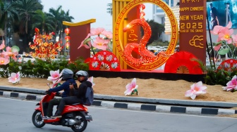 Sejumlah pengendara sepeda motor melintasi dekorasi Tahun Baru Imlek di Bundaran HI, Jakarta, Senin (27/1/2025). [Suara.com/Alfian Winanto]