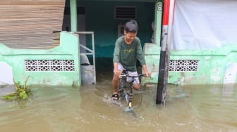 Warga beraktivitas di tengah banjir yang terjadi di pemukiman, kawasan Cakung, Jakarta, Rabu (29/1/2025). [Suara.com/Alfian Winanto]