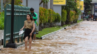 Warga melintasi banjir di Jalan Boulevard Raya, Kelapa Gading, Jakarta, Rabu (29/1/2025). [Suara.com/Alfian Winanto]