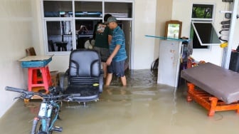 Warga beraktivitas di tengah banjir yang terjadi di pemukiman, kawasan Cakung, Jakarta, Rabu (29/1/2025). [Suara.com/Alfian Winanto]