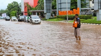 Warga melintasi banjir di Jalan Boulevard Raya, Kelapa Gading, Jakarta, Rabu (29/1/2025). [Suara.com/Alfian Winanto]