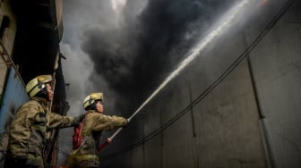 Petugas pemadam kebakaran menyemprotkan air ke arah api yang membakar salah satu gudang di kawasan pergudangan Pantai Indah Dadap, Kosambi, Kabupaten Tangerang, Banten, Jumat (31/1/2025). [ANTARA FOTO/Putra M. Akbar/app/nym]