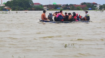 Warga menaiki perahu melintasi jalan yang tergenang banjir di Dukuh Karangturi, Desa Setrokalangan, Kaliwungu, Kudus, Jawa Tengah, Jumat (31/1/2025). [ANTARA FOTO/Ahmad Subaidi/nz]