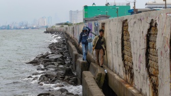 Warga beraktivitas di sekitar tanggul laut kawasan muara baru, Jakarta, Rabu (5/2/2025). [Suara.com/Alfian Winanto]