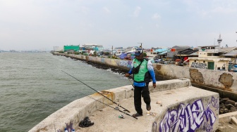 Warga beraktivitas di sekitar tanggul laut kawasan muara baru, Jakarta, Rabu (5/2/2025). [Suara.com/Alfian Winanto]