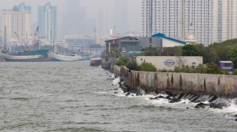 Warga beraktivitas di sekitar tanggul laut kawasan muara baru, Jakarta, Rabu (5/2/2025). [Suara.com/Alfian Winanto]