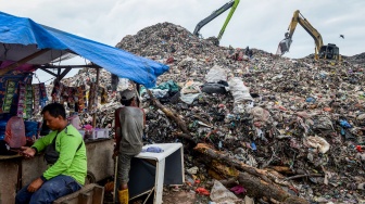 Pemulung istirahat di dekat alat berat yang mengeruk sampah di Tempat Pembuangan Akhir (TPA) Jatiwaringin, Kabupaten Tangerang, Banten, Kamis (6/2/2025). [ANTARA FOTO/Putra M. Akbar/foc]