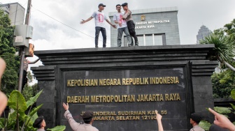 Massa dari Aliansi Rakyat Menggugat (ARM) menaiki dinding saat menggelar aksi unjuk rasa di depan Polda Metro Jaya, Jakarta, Jumat (7/2/2025). [Suara.com/Alfian Winanto]