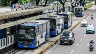 Bus Transjakarta transit di Halte Senayan, Jakarta, Rabu (12/2/2025). [Suara.com/Alfian Winanto]