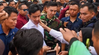 Wakil Presiden Gibran Rakabuming Raka (ketiga kiri) wajahnya dipegang warga saat membagikan alat tulis kepada warga seusai meninjau proyek terowongan di Jalan Sultan Alimudin di Samarinda, Kalimantan Timur, Rabu (12/2/2025). [ANTARA FOTO/M Risyal Hidayat/nym]