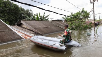 Seorang anggota Babinsa menaiki perahu untuk melihat kondisi banjir di Perumnas Antang, Makassar, Sulawesi Selatan, Rabu (12/2/2025). [ANTARA FOTO/Arnas Padda/foc]