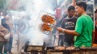 Pedagang membakar makanan yang dijual di Bazar Takjil, Bendungan Hilir, Jakarta, Senin (3/3/2025). [Suara.com/Alfian Winanto]