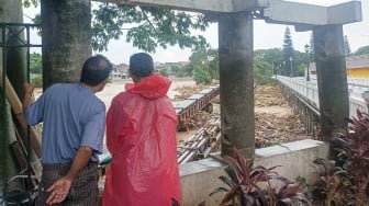 Warga melihat kondisi jembatan yang dipenuhi sampah kiriman di kawasan perumahan Kemang Pratama, Bekasi, Jawa Barat, Selasa (4/3/2025). [Suara.com/Alfian Winanto]