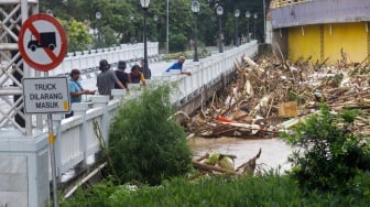 Warga melihat kondisi jembatan yang dipenuhi sampah kiriman di kawasan perumahan Kemang Pratama, Bekasi, Jawa Barat, Selasa (4/3/2025). [Suara.com/Alfian Winanto]