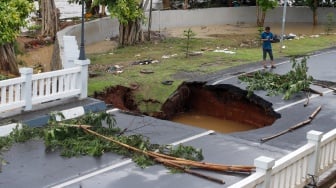 Warga melihat jembatan yang amblas di kawasan perumahan Kemang Pratama, Bekasi, Jawa Barat, Selasa (4/3/2025). [Suara.com/Alfian Winanto]