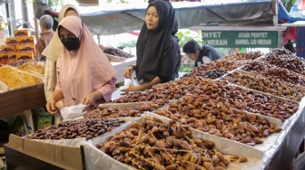 Pembeli memilih buah kurma di Pasar Tanah Abang, Jakarta, Rabu (12/3/2025). [Suara.com/Alfian Winanto]