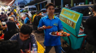 Pedagang mengantar makanan di Sentra kuliner Nasi Kapau di Jalan Kramat Raya, Senen, Jakarta, Selasa (18/3/2025). [Suara.com/Alfian Winanto]
