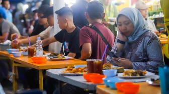 Pengunjung menunggu waktu berbuka puasa di Sentra kuliner Nasi Kapau di Jalan Kramat Raya, Senen, Jakarta, Selasa (18/3/2025). [Suara.com/Alfian Winanto]
