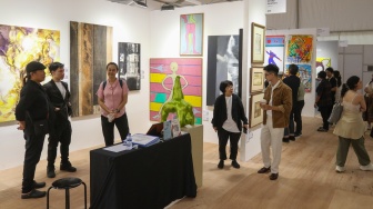 Pengunjung melihat karya instalasi seni pada Pameran Art Jakarta Gardens di Hutan Kota Plataran, Senayan, Jakarta, Jumat (25/4/2025). [Suara.com/Alfian Winanto]
