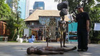 Pengunjung melihat karya instalasi seni pada Pameran Art Jakarta Gardens di Hutan Kota Plataran, Senayan, Jakarta, Jumat (25/4/2025). [Suara.com/Alfian Winanto]