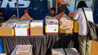 Pengunjung memilih rilisan fisik yang ditawarkan dalam acara Record Store Day Indonesia x Pop City di Senayan Park, Jakarta, Jumat (25/4/2025). [Suara.com/Alfian Winanto] 