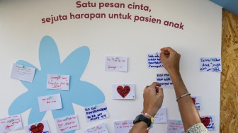 Pengunjung melihat karya instalasi seni pada Pameran Art Jakarta Gardens di Hutan Kota Plataran, Senayan, Jakarta, Jumat (25/4/2025). [Suara.com/Alfian Winanto]