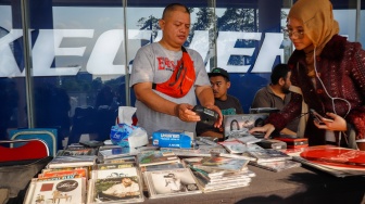Pengunjung memilih rilisan fisik yang ditawarkan dalam acara Record Store Day Indonesia x Pop City di Senayan Park, Jakarta, Jumat (25/4/2025). [Suara.com/Alfian Winanto] 