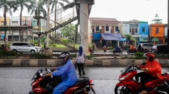 Warga menyebrang di tengah jalan raya akibat jembatan Penyeberangan Orang (JPO) Tipar Cakung yang rusak di Jakarta, Sabtu (26/4/2025). [Suara.com/Alfian Winanto]
