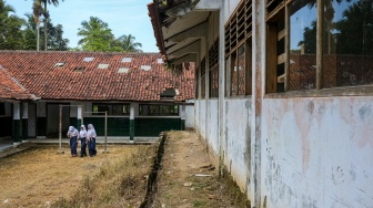Tiga siswi berjalan di dekat ruang kelas yang rusak di SMP Negeri 2 Cimanuk, Pandeglang, Banten, Senin (28/4/2025). [ANTARA FOTO/Angga Budhiyanto/rwa]