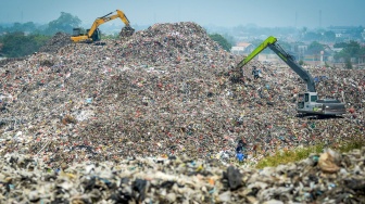 Petugas menggunakan alat berat saat mengeruk sampah di Tempat Pembuangan Akhir (TPA) Jatiwaringin, Kabupaten Tangerang, Banten, Selasa (29/4/2025). [Suara.com/Alfian Winanto]