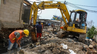 Petugas Sudin Sumber Daya Air Jakarta Utara menggunakan alat berat saat memperbaiki tembok galangan kapal yang roboh di kawasan Pluit Penjaringan, Jakarta, Selasa (29/4/2025). [ANTARA FOTO/Fathul Habib Sholeh/nym]