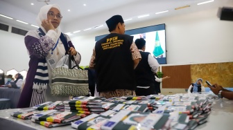 Petugas membagikan paspor calon jamaah haji di Asrama Haji Pondok Gede, Jakarta, Senin (5/5/2025). [Suara.com/Alfian Winanto]
