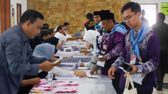 Petugas membagikan paspor calon jamaah haji di Asrama Haji Pondok Gede, Jakarta, Senin (5/5/2025). [Suara.com/Alfian Winanto]
