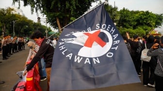 Aktivis Jaringan Solidaritas Korban untuk Keadilan membawa bendera bergambar Soeharto saat mengikuti aksi Kamisan ke-860 di depan Istana Merdeka, Jakarta, Kamis (8/5/2025). [Suara.com/Alfian Winanto]