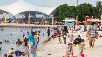 Pengunjung berwisata di Pantai Lagoon, Taman Impian Jaya Ancol, Jakarta, Selasa (13/5/2025). [Suara.com/Alfian Winanto]