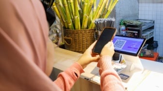 Pembeli memindai Kode Respons Cepat Standar (QRIS) di Sarinah, Jakarta, Selasa (13/5/2025). [Suara.com/Alfian Winanto]