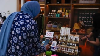 Pembeli memindai Kode Respons Cepat Standar (QRIS) di Sarinah, Jakarta, Selasa (13/5/2025). [Suara.com/Alfian Winanto]
