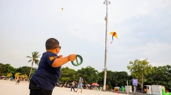 Pengunjung berwisata di Pantai Lagoon, Taman Impian Jaya Ancol, Jakarta, Selasa (13/5/2025). [Suara.com/Alfian Winanto]