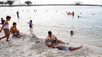 Pengunjung berwisata di Pantai Lagoon, Taman Impian Jaya Ancol, Jakarta, Selasa (13/5/2025). [Suara.com/Alfian Winanto]