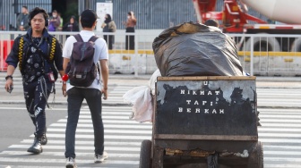 Pekerja berjalan sepulang bekerja di kawasan Jalan MH Thamrin, Jakarta, Rabu (14/5/2025). [Suara.com/Alfian Winanto]