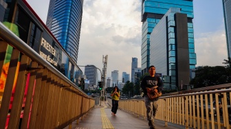 Pekerja berjalan sepulang bekerja di kawasan Jalan MH Thamrin, Jakarta, Rabu (14/5/2025). [Suara.com/Alfian Winanto]