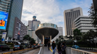 Pekerja berjalan sepulang bekerja di kawasan Jalan MH Thamrin, Jakarta, Rabu (14/5/2025). [Suara.com/Alfian Winanto]