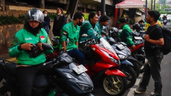 Pengemudi ojek daring menunggu penumpang di Stasiun Sudirman, Jakarta, Senin (20/5/2025). [Suara.com/Alfian Winanto]
