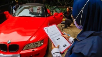 Petugas memeriksa kendaraan yang menjadi barang sitaan di Gedung Merah Putih Komisi Pemberantasan Korupsi (KPK), Jakarta, Senin (26/5/2025). [Suara.com/Alfian Winanto] 