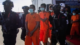 Personel Brimob menggiring tersangka kasus penyelupan sabu-sabu saat pengungkapan kasus di Pelabuhan Bea Cukai Batam, Kepulauan Riau, Senin (26/5/2025). [ANTARA FOTO/Teguh Prihatna/Spt]