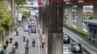 Pengendara melintas di dekat tiang bekas proyek monorel Jakarta di kawasan Jalan HR Rasuna Said, Jakarta, Senin (2/6/2025). [Suara.com/Alfian Winanto]