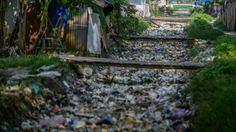 Seorang anak berjalan diatas di saluran irigasi yang dipenuhi sampah di Desa Susukan, Kabupaten Serang, Banten, Senin (2/6/2025). [ANTARA FOTO/Muhammad Bagus Khoirunas/bar]