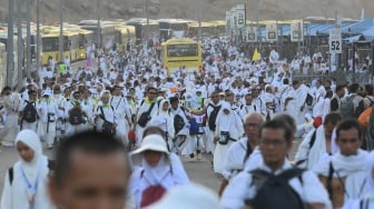 Jemaah haji dari berbagai negara termasuk Indonesia berjalan kaki di samping deretan bus yang tidak bisa bergerak karena terjebak kemacetan di Muzdalifah, Makkah, Arab Saudi, Jumat (6/6/2025). [ANTARA FOTO/Andika Wahyu/foc]