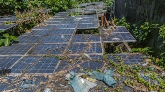 Seorang anak membersihkan rumput di sekitar panel Pembangkit Listrik Tenaga Surya (PLTS) yang rusak di Ternate, Maluku Utara, Senin (9/6/2025). [ANTARA FOTO/Andri Saputra/bar]